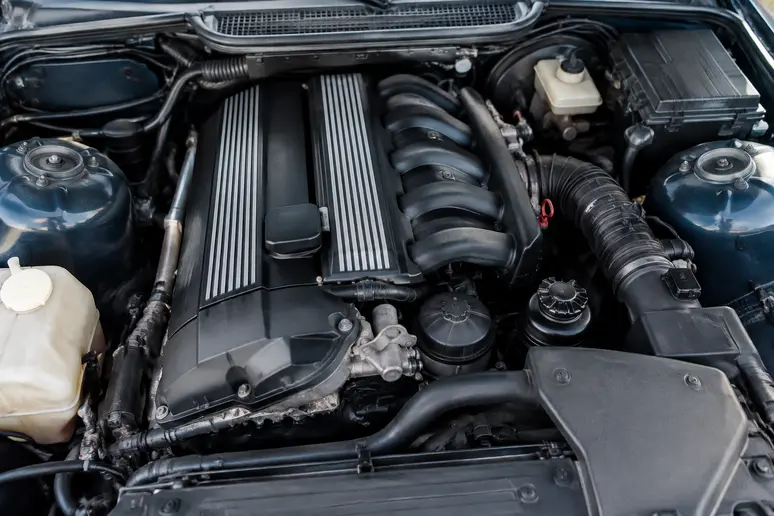 Compartiment moteur propre d'une BMW E36 six cylindres montrant l'état mécanique général.