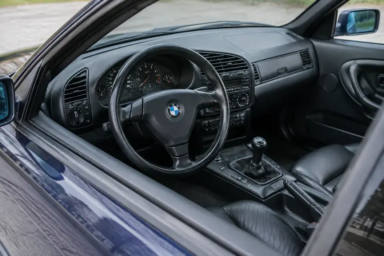 Habitacle d'un coupé BMW E36 d'origine avec volant sport et tableau de bord classique.