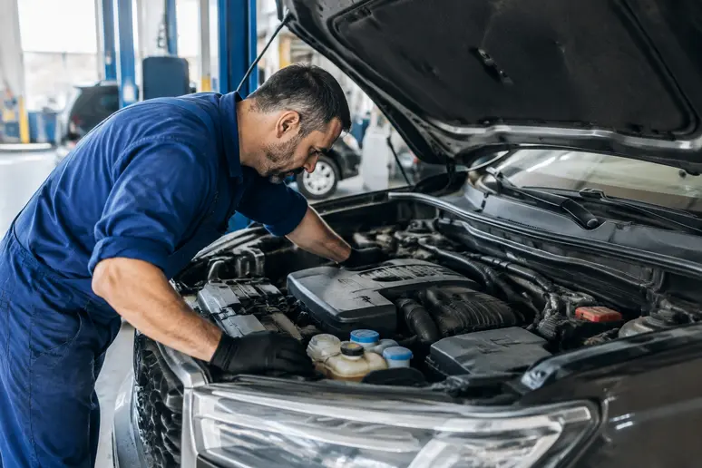 Mécanicien inspectant le moteur d'un Nissan Qashqai d'occasion dans un atelier lumineux