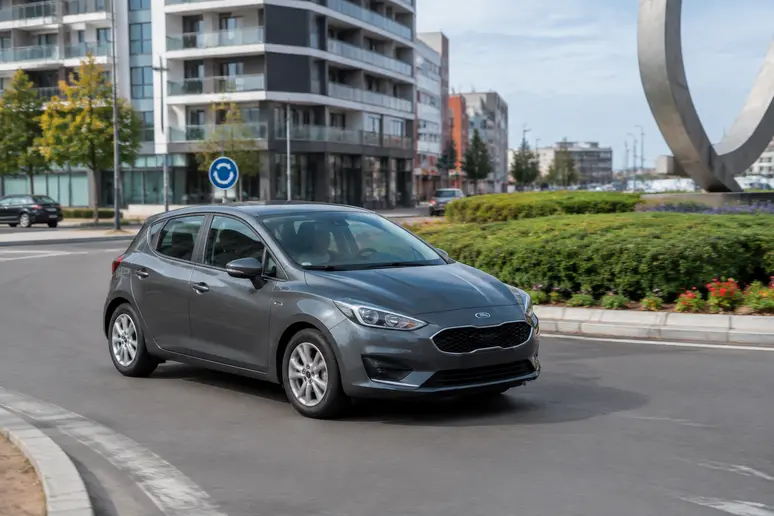 Citadine d'occasion roulant sur un rond-point en zone urbaine.
