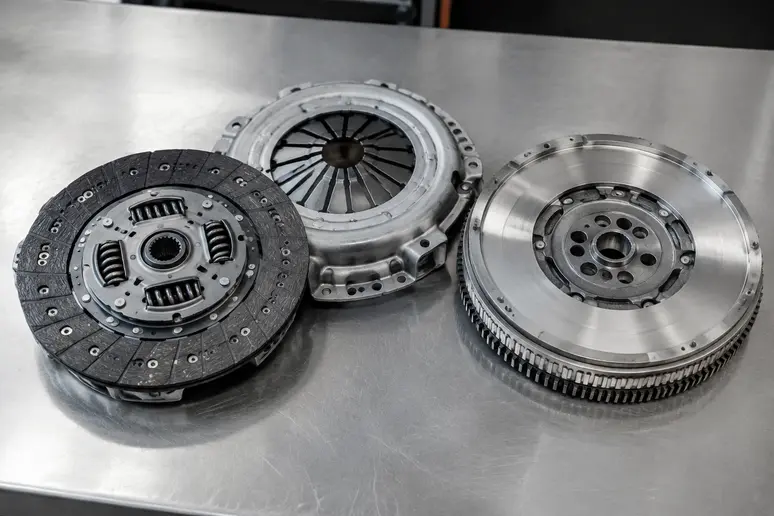 Kit d'embrayage et volant moteur bi-masse présentés côte à côte sur un établi métallique
