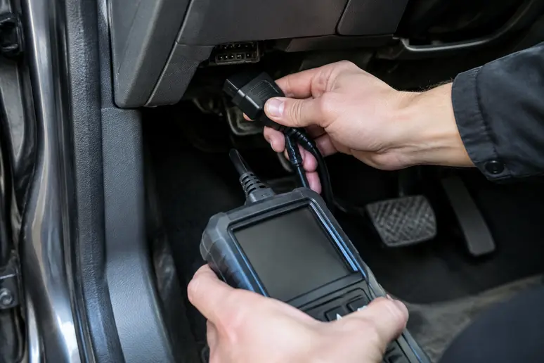 Mains branchant un outil de diagnostic sur la prise OBD d'une voiture d'occasion