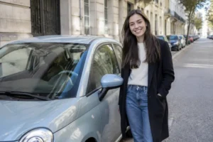 Un jeune conducteur souriant à côté d'une voiture occasion jeune conducteur garée en ville.