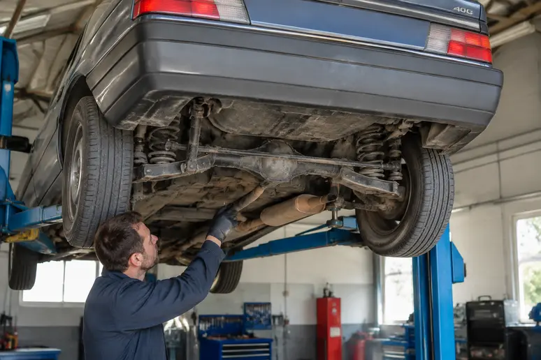 Inspection du train arrière d'une Peugeot 405 sur un pont élévateur en atelier