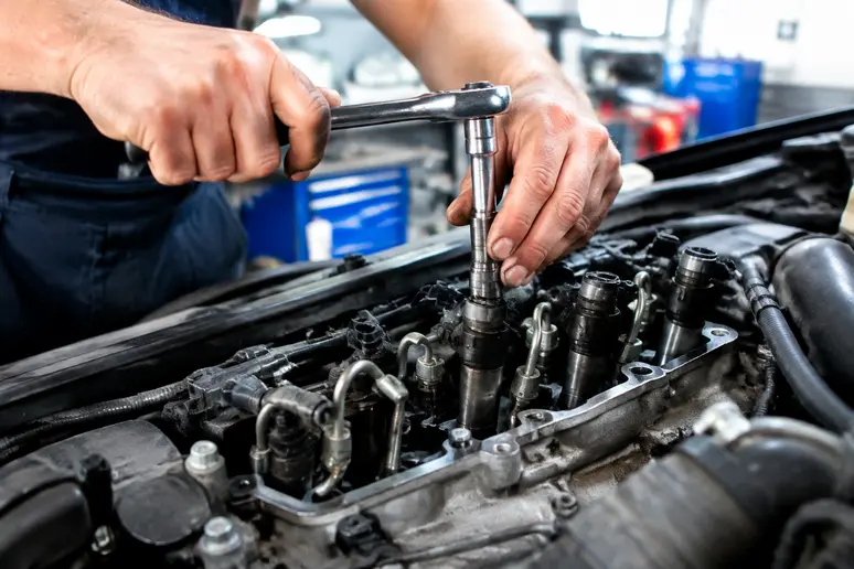 Mécanicien démontant un injecteur diesel défectueux sur le bloc moteur d'une voiture