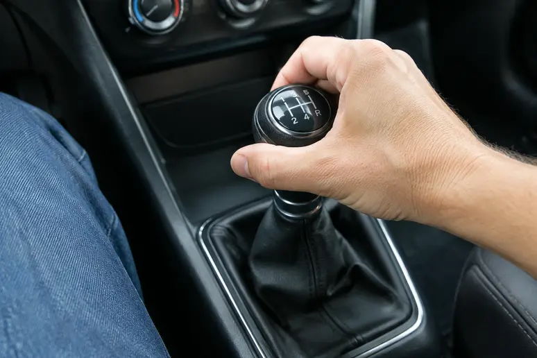 Main d'un conducteur testant le passage des rapports sur une boîte manuelle de Hyundai i20 d'occasion.
