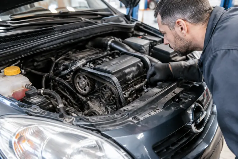 Vérification des éléments moteurs sous le capot d'une Opel Corsa d'occasion lors de l'inspection.