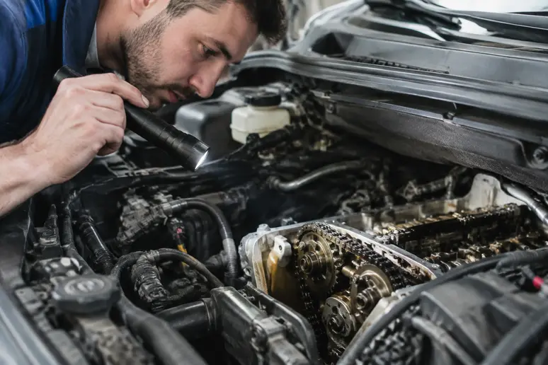 Mécanicien inspectant le compartiment moteur d'une voiture pour détecter l'usure de la chaîne de distribution